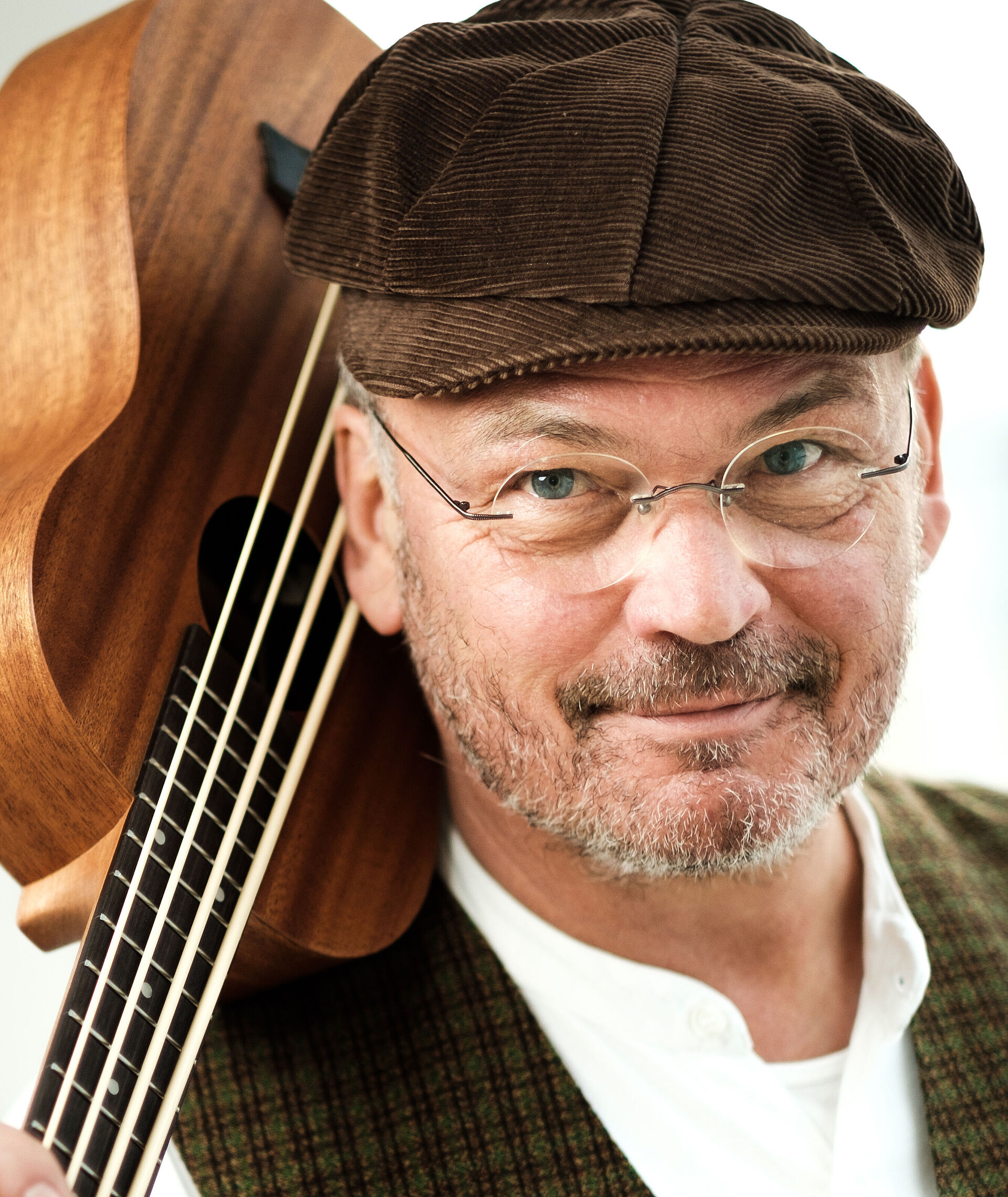 Ein Mann mit Kappe auf und Gitarre auf der Schulter.