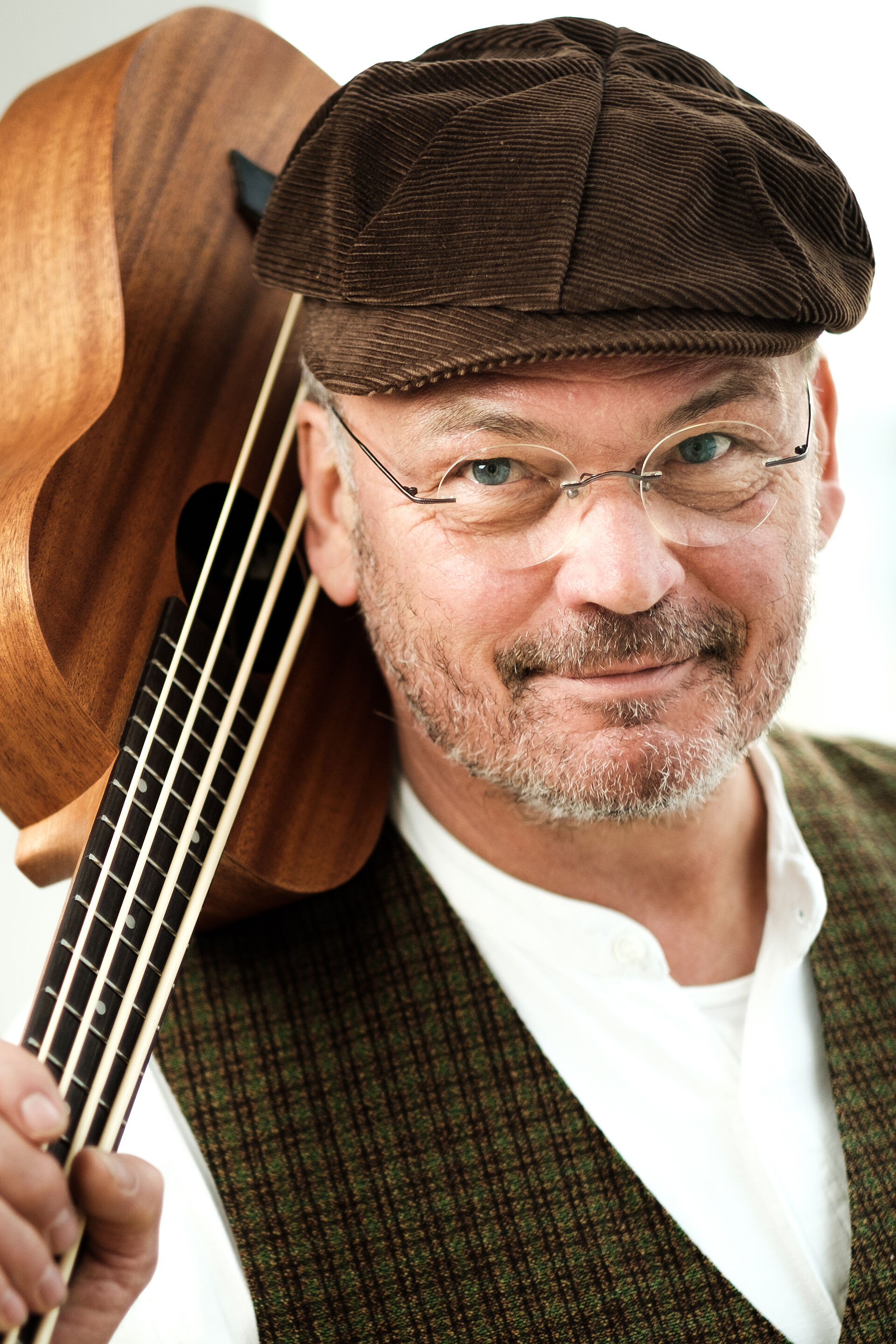 Ein Mann mit Kappe auf und Gitarre auf der Schulter.