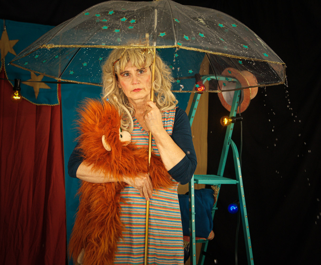 Eine Frau mit blonden Locken unter einem leuchtenden Regenschirm.