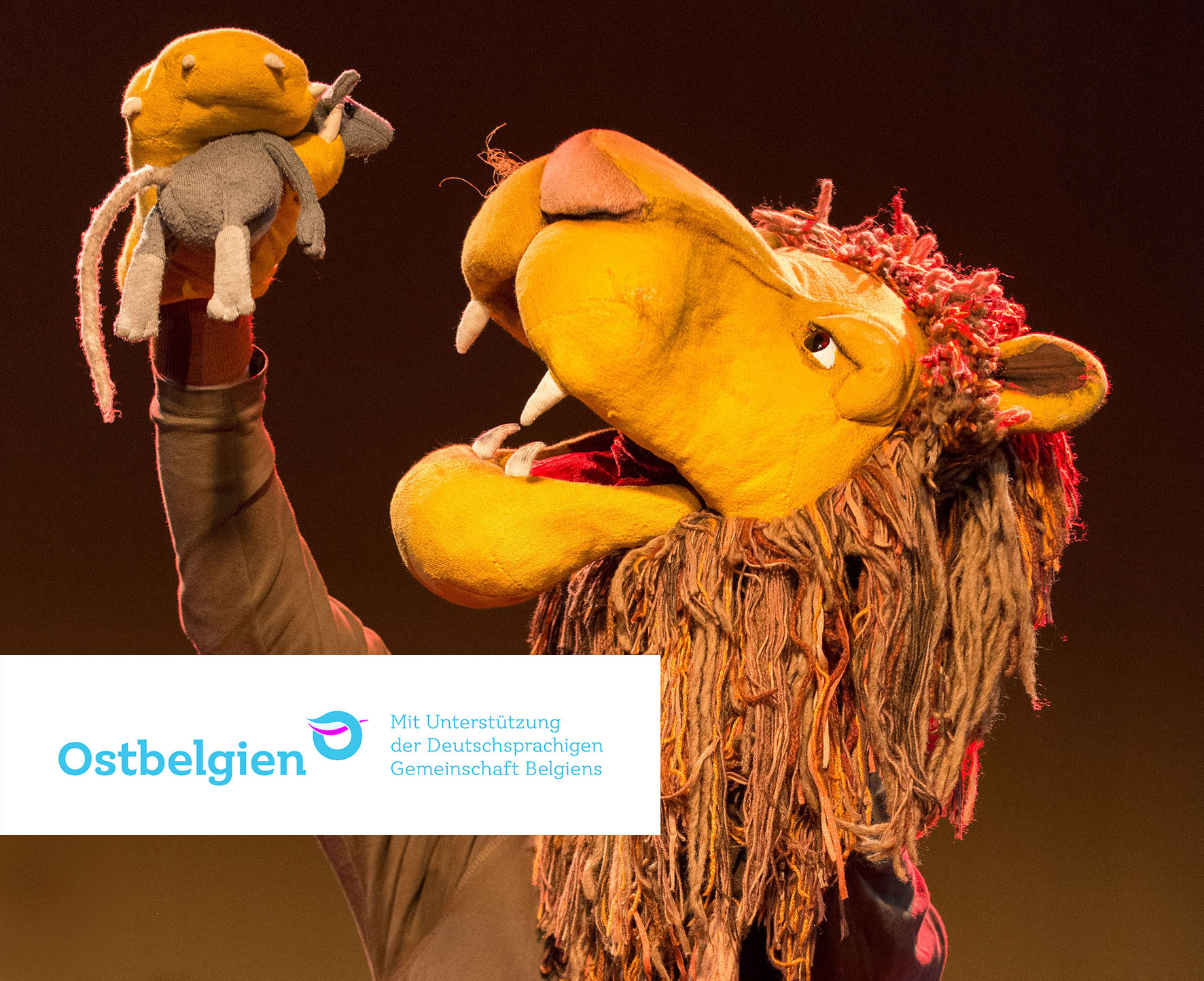 Ein Stofflöwe mit einer Stoffmaus in der Pfote.