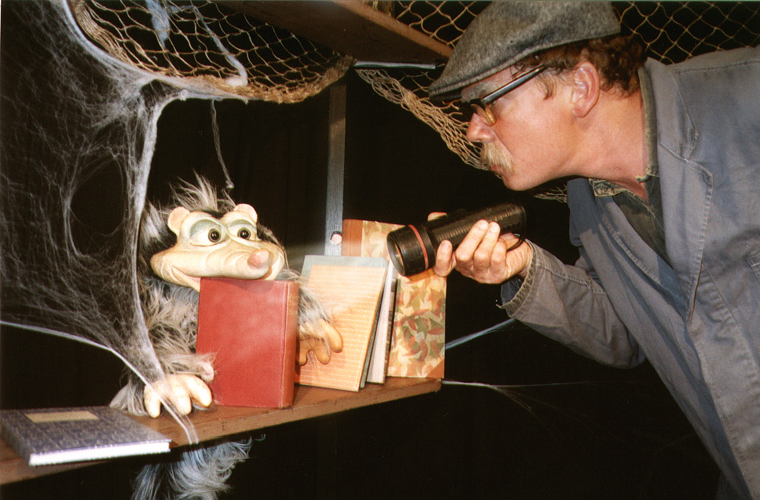 Ein Mann erkundet ein mit Spinnweben überzogenes Regalbrett.